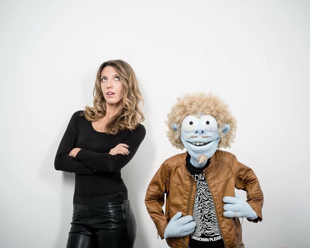 Salomé, bras croisés, à côté d'une marionnette, photo promo de Top Streaming
